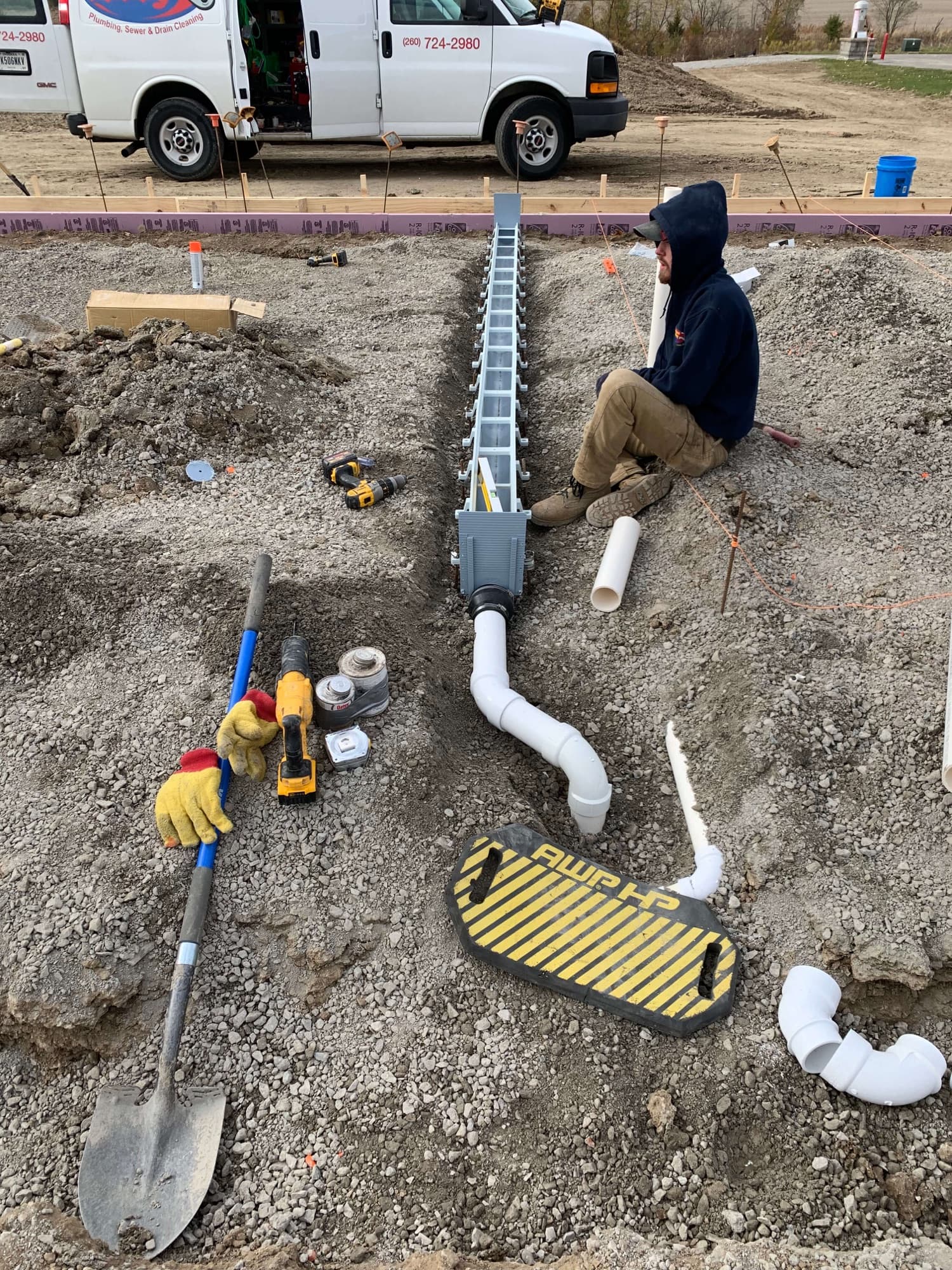 Andrews Plumbing crew installing drain lines on a job site, company van in the background